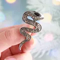 Elegant vintage snake brooch pin featuring champagne rhinestones and black gem eye - Gun Black