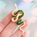 Elegant gold-toned snake brooch adorned with sparkling emerald green crystal stones - Gold with Green Stone