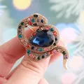 Elegant snake-shaped brooch with colorful rhinestones and a large blue pear-cut stone - Gold with Multicolor Zircon