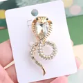 Elegant gold-tone snake brooch adorned with rhinestones and a heart-shaped crystal - Gold with White Zircon