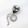 Silver-toned snake brooch with shimmering rhinestones and a large black pear-shaped gem - Silver Black Rhinestone