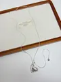 Close-up detail of a minimalist silver metallic heart pendant necklace on a wooden tray - Silver Textured Heart