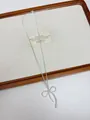 Close-up of a minimalist silver bow pendant necklace on a wooden display tray. - Silver Bowknot