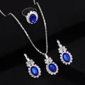 Elegant silver jewelry set with oval blue gemstones and halo diamonds in black background - Three-Piece Set / 8411 Blue