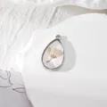 Vue détaillée du pendentif goutte en résine avec fleurs séchées jaunes et cadre en argent - Imprimé Fleuri Blanc Cassé