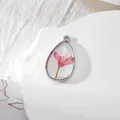 Dettaglio ravvicinato di un ciondolo a goccia in resina con fiore rosa e cornice argento - Fiore Rosa