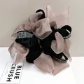 Detalle macro de coletero de organza negra con lazo multicapa e incrustaciones de strass - Rosa Loto
