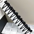 Macro shot of 10 black bow hair clips with shiny rhinestones on a display card - Rhinestone Strip Waterdrop Clip Bow