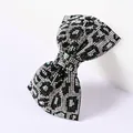 Gros plan d'une pince à cheveux nœud à motif léopard sertie de strass brillants - Léopard Noir