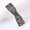 Close-up of bow-shaped hair clip with sparkling triangular rhinestones and black alloy base - Gray