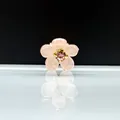 Vista macro de la pequeña pinza de flor rosa translúcida con centro de diamantes dorados - Rosa Con Strass
