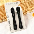 Juego de dos pinzas negras con purpurina y diseño calado en tarjeta blanca - Estilo Lazo Grande Hueco (NM-425) / Juego de 2 Piezas / Negro