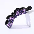Dettaglio del fermaglio a banana con strass viola su un supporto bianco minimalista - Viola
