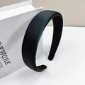 Dettaglio di un ampio cerchietto imbottito nero satinato appoggiato su un libro bianco - Cerchietto in Spugna Liscia da 2.7cm / Nero
