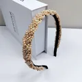 Detailed side view of champagne pearl headband with woven design on velvet base - Champagne