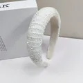 Close-up of padded headband featuring dense white faux pearls and clear faceted beads texture - White