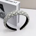 Detalle de diadema acolchada con cristales brillantes y perlas blancas sobre terciopelo - Blanco