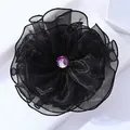 Gros plan sur une élégante pince à cheveux fleur en mousseline noire avec strass brillant - Noir