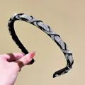 Macro detail of hand-held braided headband with sparkling crystals on black fabric - White Zircon