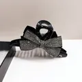 Gros plan d'une grande pince à cheveux noire avec des nœuds en strass brillants - Gris Transparent