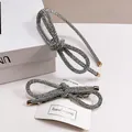 Detailweergave van zilveren strass strik haarrand en haarclip set op sieradenkaart - Cijfer 8 Set (Haarband + Veerspeld)