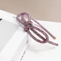 Macro detail of a knotted purple rhinestone headband with shimmering crystals and gold ends - Pink