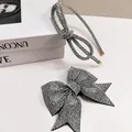 Detalle del conjunto de pasador y diadema con lazo de diamantes de imitación en un libro - Diadema Infiniti Y Pinza De Resorte De Cola De Golondrina