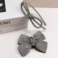 Vista de detalle del clip de lazo con pedrería brillante y el conjunto de diadema de plata - Diadema Infiniti Y Pinza De Resorte Con Lazo Cruzado
