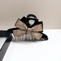 Elegant large black hair claw clip featuring a luxurious gold rhinestone-encrusted bow - Champagne