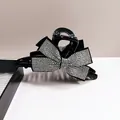 Elegant black hair claw clip featuring a large silver rhinestone bow design for women - White