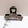 Macro detail of a sparkling bow hair claw clip with champagne rhinestones on black - Full Rhinestone Small Bow Style / Champagne