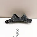 Détail de la pince banane nœud noir ornée de strass argentés étincelants sur base brillante - Bleu Marine