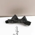 Close-up of a black bow banana clip with shimmering silver rhinestones on a white box - Black