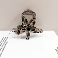 Primer plano de una pinza para el pelo floral de carey con perla negra y acetato - Flor de leopardo