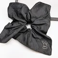 Dettaglio ravvicinato dello scrunchie in denim scuro con ornamento animale in strass - Decorazione Animale in Strass / Nero