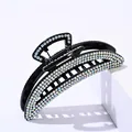 Close-up of elegant black hair claw clip with shimmering rhinestones on white stand - Crescent Colorful Rhinestone