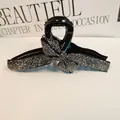 Close-up of a black hair claw clip featuring a sparkling rhinestone bow design - Mineral Grey Rhinestone