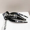 Macro shot of black glossy hair clip featuring sparkling crystal flowers and rhinestones - Claw Clip (Swallowtail Crystal)