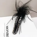 Detail view of a black feather hair claw clip with rhinestones on a white book - Claw Clip (Feather Crystal)