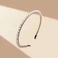 Detalle macro de una diadema de metal dorado con perlas blancas elegantes y puntas negras - Estilo Simple de Una Fila de Perlas Doradas (11-2-5)