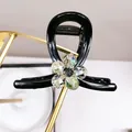 Detail of elegant black resin hair claw with crystal flower motif on a gold display - Green Crystal Flower Medium Claw Clip