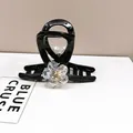 Detail of elegant black resin hair claw clip with shimmering crystal flower and gold accents - Medium Hair Claw / White Crystal