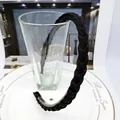 Detail of black braided headband with anti-slip inner teeth on white ceramic plate - Black