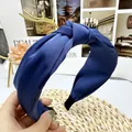 Detail of navy blue satin knot headband featuring cross-over design and fine texture - Navy Blue