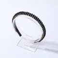 Detalle de diadema negra fina con pedrería iridiscente multicolor sobre un soporte transparente - Negro