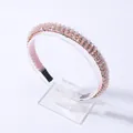 Detalle de diadema rosa con cuentas y cristales brillantes en soporte de exhibición - Rosa