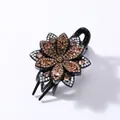 Macro shot of retro flower hair claw with amber rhinestones on a black glossy base - 6-Petal Flower (Champagne Rhinestone)