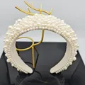 Close-up of luxury padded headband with white faux pearls on a gold display stand - White