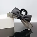 Detail einer eleganten schwarzen Schleifen-Haarklammer mit funkelndem Strassstein-Besatz - Transparent grauer Strass