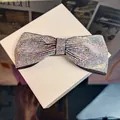 Macro shot of sparkling AB crystal bow hair clip with black fabric edges on white box - Colorful